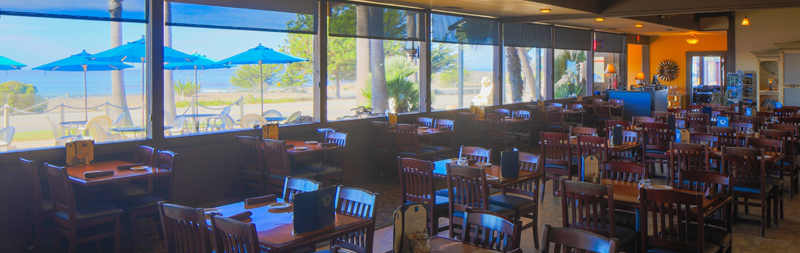 tables and chairs inside restaurant with ocean view